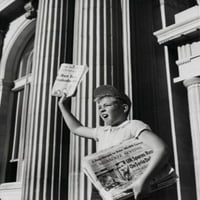 Dječak prodaje novine ispred zgrade za plakat