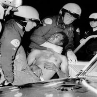 Policajci prisiljavaju čovjeka u policijski automobil tokom nereda u povijesti Watts