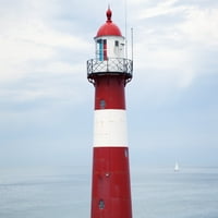 Crveni i bijeli svjetionik uz obalu sa jedrilom u udaljenosti u blizini Westkapelle; Zeland, Holandski poster Print